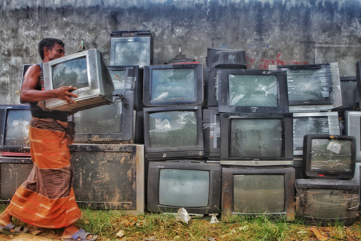 Photo of a woman dealing with discarded TV's in a 3rd world country